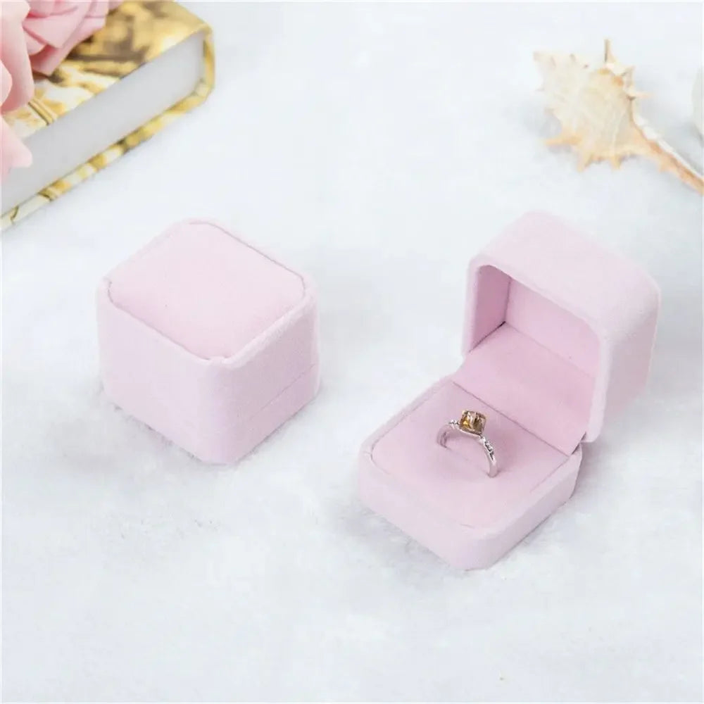 Moissanite engagement ring in pink velvet box on white background, elegant jewelry display