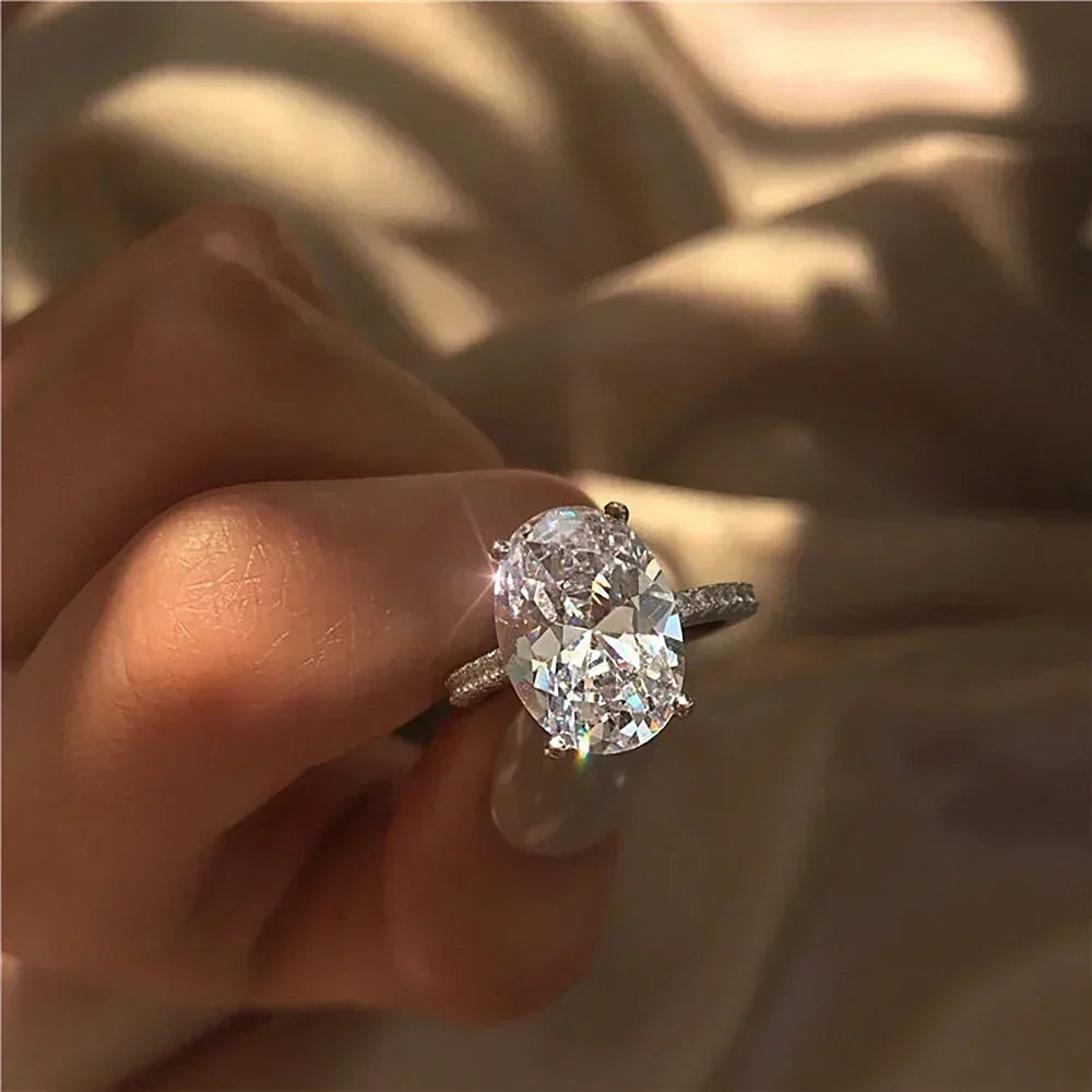 Hand holding an oval moissanite engagement ring with a sparkling lab-made stone