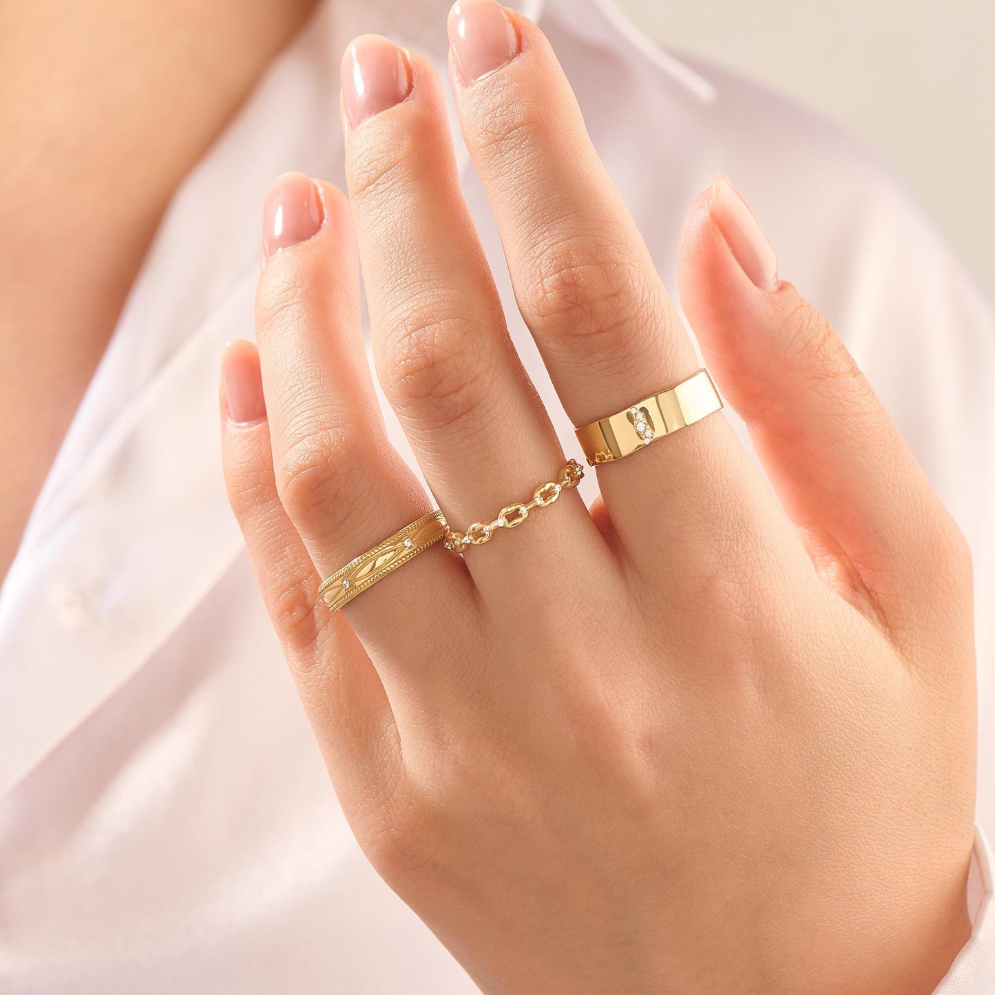 Hand wearing three elegant gold moissanite rings, showcasing fine jewelry detail