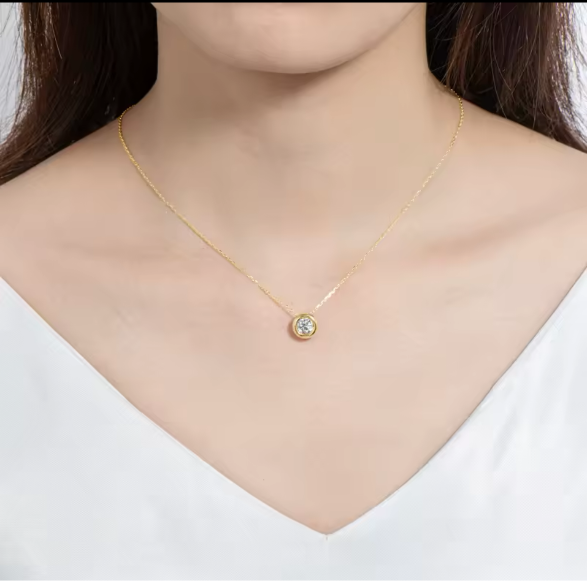 Model wearing a gold plated sterling silver moissanite necklace with a 2 carat circle cut VVS clarity, for women.